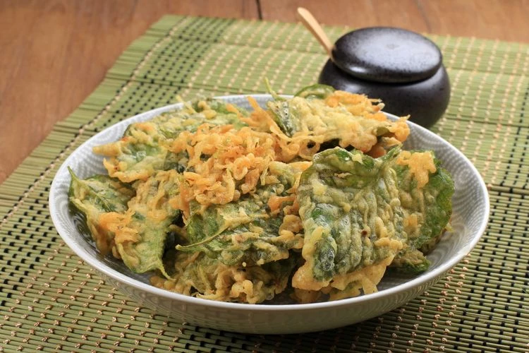 Keripik bayam merupakan keripik yang terbuat dari daun bayam yang digoreng menggunakan tepung yang sudah dibumbui. Umumnya rasanya yaitu asin dengan aroma bawang yang gurih. Nah, dalam artikel ini akan dibahas mengenai resep keripik bayam tidak berminyak yang harus kamu coba di rumah. Keripik bayam ini menjadi salah satu camilan yang begitu digemari masyarakat karena bahan baku pembuatannya bisa dikembangkan di daerah dataran tinggi maupun daerah dataran rendah. Di sisi lain, keripik bayam adalah salah satu alternatif camilan yang sehat untuk dikonsumsi. Konsumen keripik bayam juga tak sekadar terpaku pada orang-orang tertentu karena mencakup kalangan anak-anak, orang dewasa, hingga orang tua. Oleh karena itu, banyak ibu rumah tangga yang melakukan produksi rumahan camilan keripik bayam menjadi satu jenis usaha industri rumah tangga yang lumayan membantu kebutuhan masyarakat yang mengembangkannya. Industri rumah tangga ini sekarang ini sudah berkembang luas di beragam wilayah di Indonesia. Resep Keripik Bayam Tidak Berminyak yang Wajib dicoba! Tanaman bayam pada awalnya masuk ke daerah Nusantara pada abad ke-14. Tanaman ini dapat dibudidayakan di wilayah dataran rendah maupun wilayah dataran tinggi. Oleh karena itu, tak heran kalau banyak orang yang kemudian memberdayakan tanaman ini menjadi beragam olahan yang dapat dikonsumsi serta bernilai ekonomi bagi masyarakat. Keripik bayam adalah salah satu camilan khas Indonesia yang lumayan terkenal. Selain karena enak dan renyah, keripik bayam juga sehat serta kaya akan nutrisi. Kalau keripik bayam ini disimpan dengan benar pada tempat kering serta tertutup rapat, bisa tahan sampai bulanan. Tetapi pada tempat terbuka, hanya akan bertahan sekitar tiga hari saja. Walaupun mengolahnya terlihat sederhana, tetapi sebenarnya ada trik khusus supaya hasilnya betul-betul enak serta tidak berminyak. Mau tahu? Mari simak artikel resep keripik bayam tidak berminyak di bawah ini. Bahan utama : 100 gr daun bayam 250 gr tepung beras 50 gr tepung tapioka 1 butir telur syam 250 ml air mineral Bumbu halus : 4 siung bawang putih 2 butir kemiri 2 cm kunyit 1 sdt garam 0,5 sdm ketumbar Langkah pembuatan : 1. Pertama ambil bayam lalu cuci bersih dan keringkan.Kemudian siapkan ulekan, dan masukan semua bahan-bahan tersebut. Haluskan hingga menjadi bumbu halus. Sisihkan dahulu. 2. Setelah itu, sediakan wadah dan masukan tepung beras, tepung tapioka, bumbu halus dan serta air mineral. Aduk merata sampai benar-benar tidak kalis. 3. Siapkan wajan, lalu panaskan minyak goreng yang cukup banyak. Setelah mendidih ambil tiap 1 lembar bayam, celupkan ke dalam adonan, dan goreng. 4. Goreng kurang lebih selama sekitar 3 menit hingga matang. Atau tanda lain kalau sudah matang dapat lihat buih minyak, kalau sudah tak berbuih itu artinya telah matang. 5. Jajarkan dengan vertikal atau berdiri keripik bayam dalam loyang oven, lalu oven pada suhu 130 derajat celsius selama sekitar 30 menit. Minyak pun akan hilang, keripik bayam siap dihidangkan! Catatan : Untuk alternatif dari langkah ke-5, kalau tidak mempunyai oven, kamu bisa menjemur sekitar dua sampai tiga jam. Tutup plastik bening kalau perlu agar tetap bersih. Dengan beberapa bahan dan juga langkah-langkah di atas, kamu sudah bisa membuat keripik bayam yang tidak berminyak. Bagaimana? Gampang sekali bukan cara membuat keripik bayam supaya tidak berminyak?  Resep Keripik Bayam Tidak Berminyak Super Renyah dan Enak Bahan – Bahan : Daun bayam merah 3 buah bawang putih 1/2 kg tepung beras 3 buah kemiri 2 ruas jari kunyit Penyedap rasa Air Garam Cara Membuat Resep Keripik Bayam Tidak Berminyak : 1. Pertama ambil bagian daun yang utuh, lalu cuci bersih, tiriskan hingga benar – benar kering ya. 2. Setelah itu, haluskan bumbu – bumbunya, sampai halus. 3. Buatlah adonan tepungnya, hingga cair sedikit kental. Jadi nanti akan menempel pada bayam, tapi tidak akan ketebelan. 4. Jangan sampai lupa untuk menambahkan daun jeruk yang cincang lembut. 5. Goreng menggunakan minyak panas, hingga sedikit menguning. 6. Untuk cara meniriskannya, Pertama angkat dari penggorengqan, lalu di taruh di atas kertas minyak (dapat juga memakai tisu goreng). Ingat ya jangan ditumpuk-tumpuk, supaya keripik tidak  menjadi berminyak. Untuk cara meniriskan minyaknya kamu juga bisa menggunakan mesin peniris minyak lho. Mesin ini akan meniriskan keripik buatanmu dari minyak yang menempel, sangat cocok untuk kamu yang sedang membuka usaha keripik. 7. Biarkan selama beberapa menit, hingga keripik bayam tak mengkilat. 8. Keripik bayam sudah siap untuk di sajikan Manfaat Bayam untuk Kesehatan Manusia 1. Sumber Nutrisi Untuk Otak Tahukah kamu kalau otak kita juga mmebutuhkan nutrisi supaya bisa bekerja dengan baik. Daun bayam kaya akan kandungan vitamin serta senyawa organik yaitu vitamin B1, vitamin B6, dan vitamin B12. 2. Menekan Risiko Diabetes Bayam bukan hanya baik di konsumsi orang sehat tapi baik untuk dikonsumsi penderita diabetes. Ternyata bayam tinggi akan kandungan senyawa yang bernama kaempferol. Senyawa ini di percayai mempunyai efek anti-inflamasi, serta anti diabetes. 3. Kesehatan Kulit Dan Rambut Selain untuk kesehatan, ternyata bayam juga mempunyai manfaat baik untuk kecantikan, kandungan vitamin A dalam bayam berfungsi untuk meyeimbangkan produksi minyak dalam pori-pori serta kulit kepala rambut. Itulah tadi artikel mengenai resep keripik bayam yang tidak berminyak beserta beberapa manfaat bayam baik untuk kesehatan maupun kecantikan, semoga bermanfaat yaa!